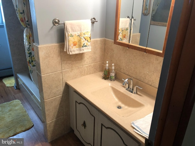 bathroom with shower / tub combo, a wainscoted wall, wood finished floors, vanity, and tile walls