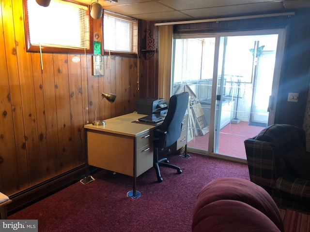 carpeted office space with a paneled ceiling and wood walls