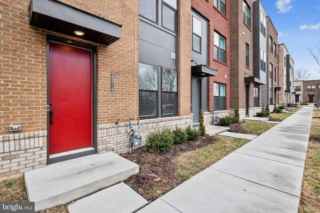 doorway to property featuring brick siding and a residential view