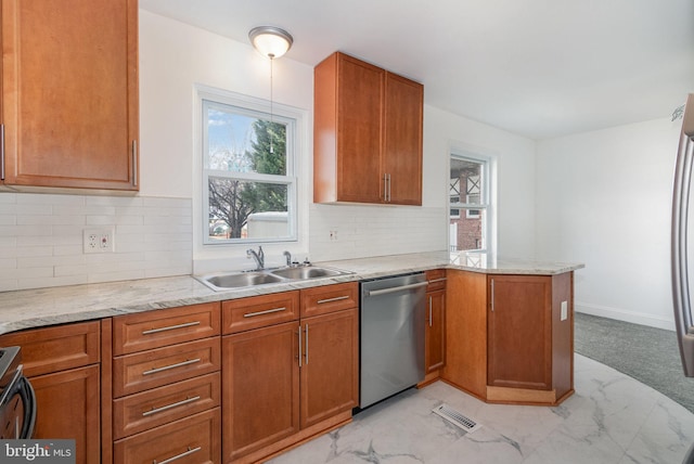 kitchen featuring brown cabinets, a sink, a peninsula, and stainless steel dishwasher