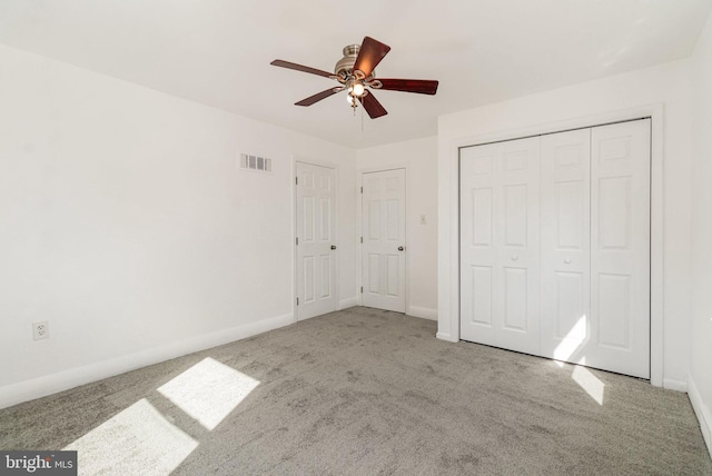 unfurnished bedroom featuring a closet, visible vents, a ceiling fan, carpet flooring, and baseboards