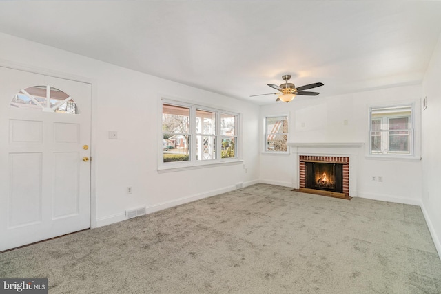 unfurnished living room featuring visible vents, baseboards, a ceiling fan, carpet, and a fireplace