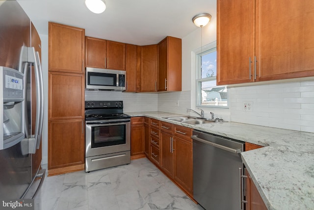 kitchen with marble finish floor, appliances with stainless steel finishes, a sink, and brown cabinets