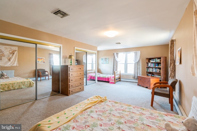 bedroom featuring a baseboard radiator, visible vents, multiple closets, and light colored carpet