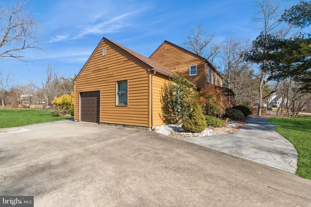 view of side of home featuring concrete driveway, a lawn, and an attached garage