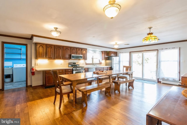 dining area featuring dark wood-type flooring, a healthy amount of sunlight, a baseboard heating unit, and crown molding