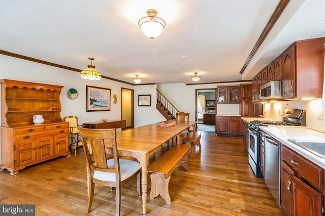 kitchen featuring light countertops, appliances with stainless steel finishes, wood finished floors, and glass insert cabinets