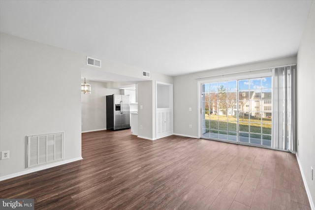 unfurnished living room featuring visible vents, baseboards, and dark wood-type flooring