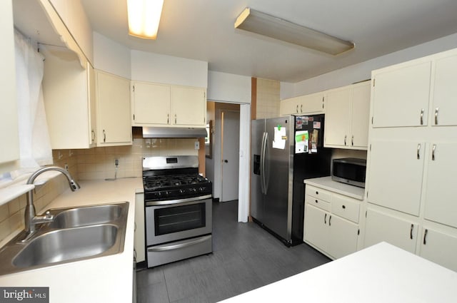 kitchen with light countertops, backsplash, appliances with stainless steel finishes, a sink, and under cabinet range hood