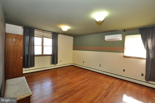 empty room with a baseboard radiator, baseboard heating, wood finished floors, and a wall mounted air conditioner