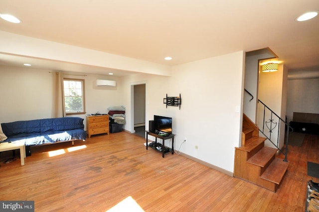 living area featuring a wall unit AC, recessed lighting, baseboards, light wood-style floors, and stairway