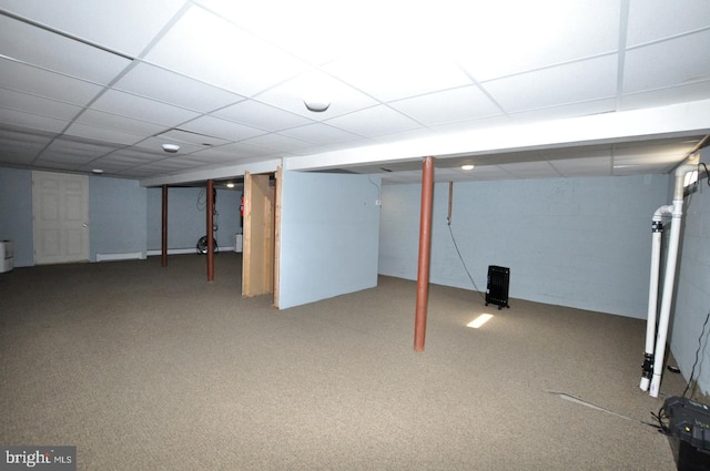 finished basement featuring carpet floors, concrete block wall, and a paneled ceiling