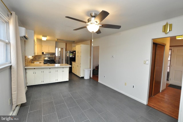 kitchen featuring stainless steel range with gas cooktop, light countertops, freestanding refrigerator, a sink, and a peninsula