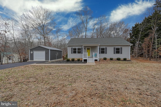 ranch-style home with aphalt driveway, covered porch, a front yard, a garage, and an outdoor structure