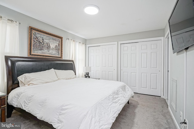 carpeted bedroom featuring multiple closets and baseboards