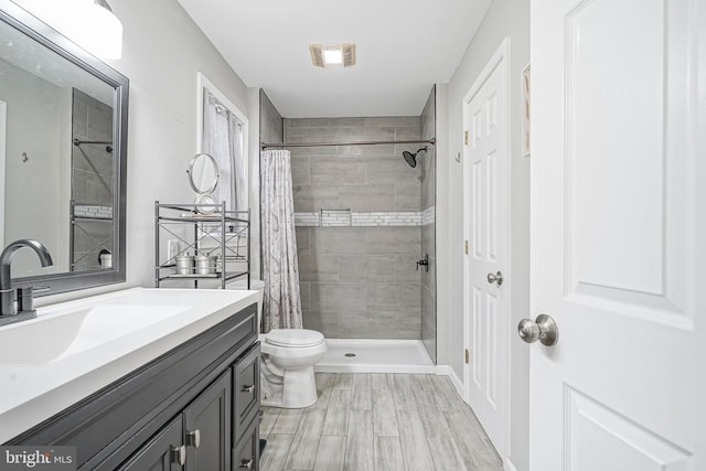 full bath featuring visible vents, toilet, a tile shower, and vanity