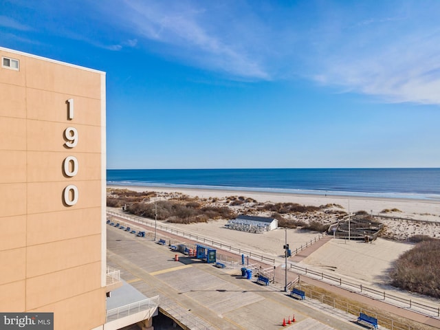 view of water feature featuring a view of the beach and fence