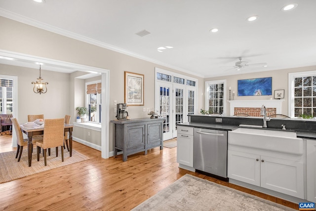 kitchen featuring a sink, french doors, stainless steel dishwasher, light wood finished floors, and dark countertops