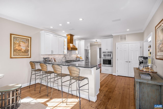 kitchen with custom exhaust hood, stainless steel appliances, visible vents, backsplash, and a peninsula