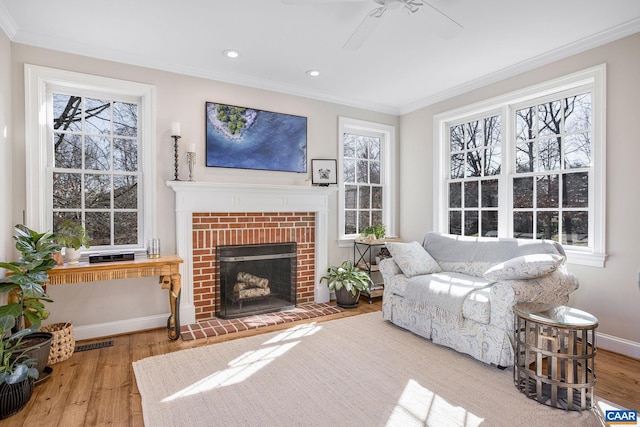 living room with baseboards, visible vents, ornamental molding, wood finished floors, and a fireplace