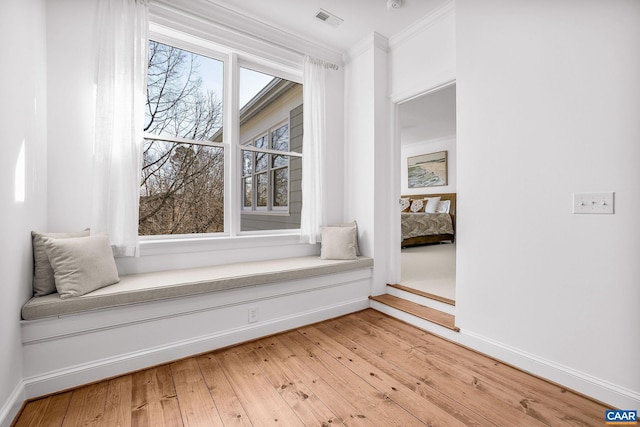 sitting room featuring baseboards, ornamental molding, visible vents, and light wood-style floors