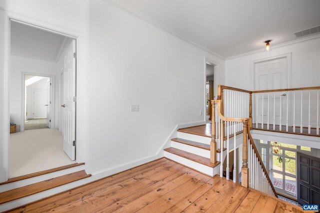 stairway with baseboards, visible vents, crown molding, and hardwood / wood-style floors