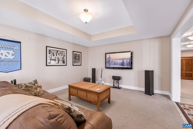 living room with light carpet, baseboards, and a tray ceiling