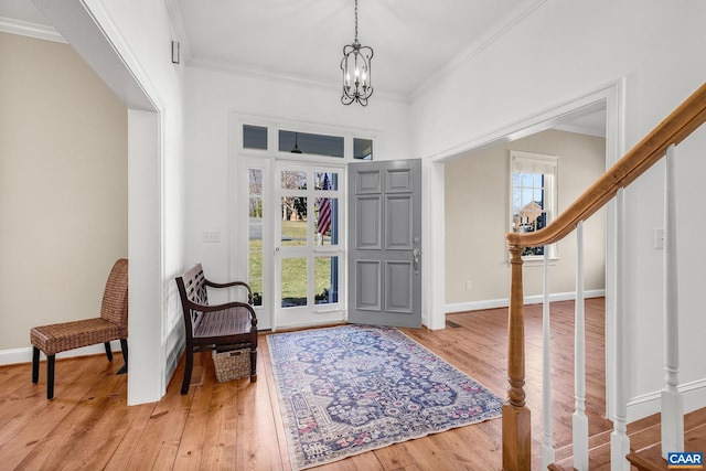 foyer entrance with crown molding, wood-type flooring, a chandelier, baseboards, and stairs