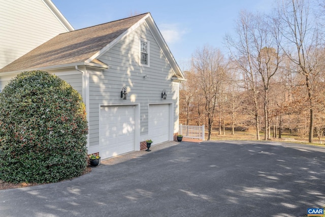 view of side of property featuring a garage and a shingled roof