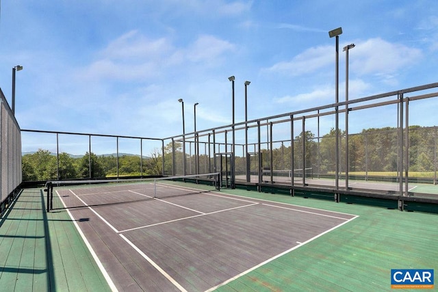 view of tennis court featuring community basketball court and fence