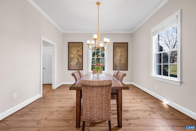 dining room featuring light wood-style floors, ornamental molding, baseboards, and an inviting chandelier