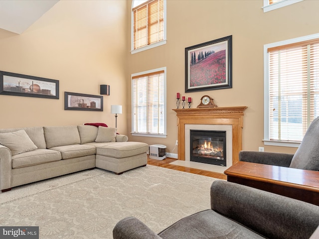 living area featuring a healthy amount of sunlight, a fireplace with flush hearth, and a towering ceiling