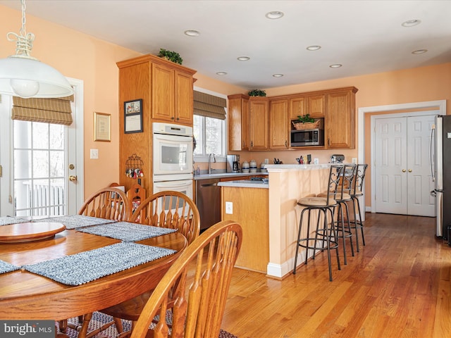 kitchen with light wood finished floors, a breakfast bar, a center island, stainless steel appliances, and light countertops