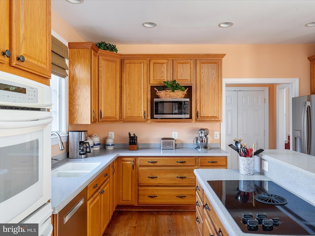 kitchen featuring wood finished floors, stainless steel appliances, a sink, and light countertops