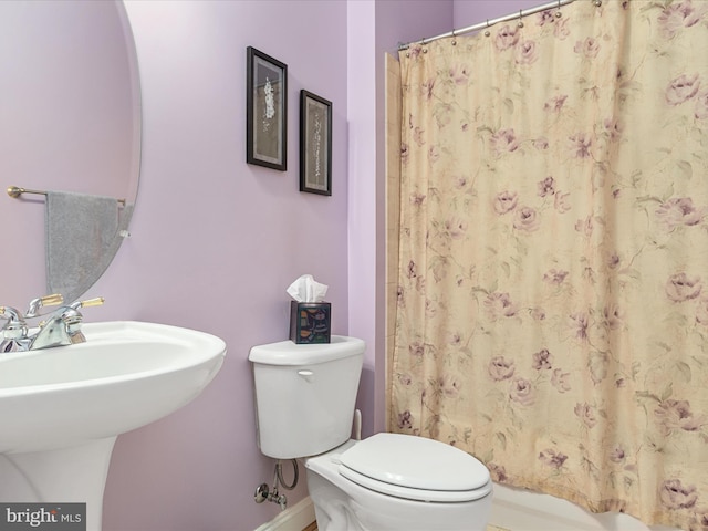 full bath featuring curtained shower, a sink, toilet, and baseboards