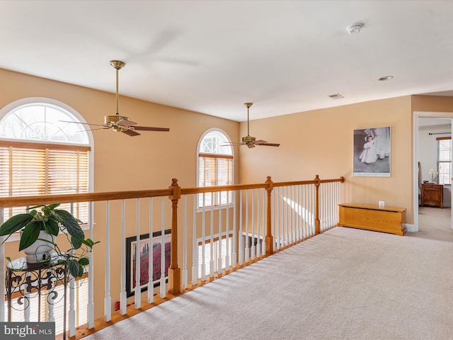 hallway with visible vents, carpet, a wealth of natural light, and baseboards