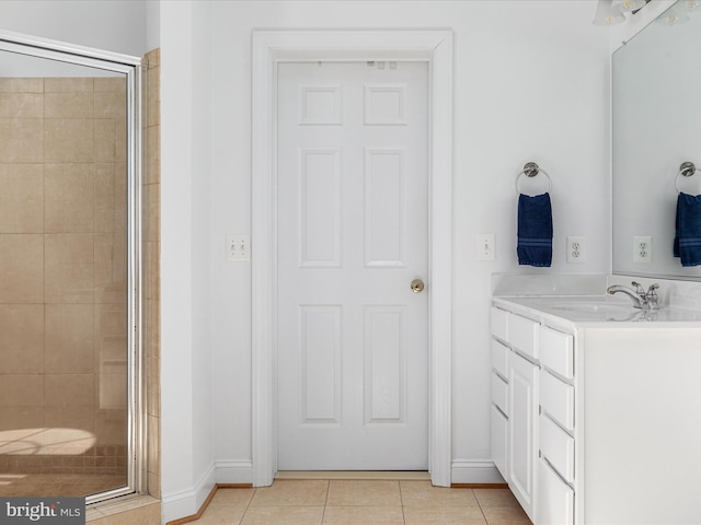 bathroom featuring tile patterned flooring, baseboards, a shower stall, and vanity