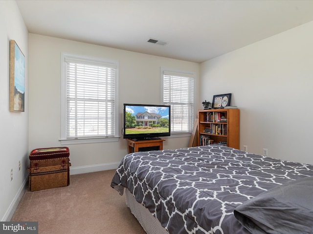 bedroom featuring baseboards, multiple windows, visible vents, and carpet flooring