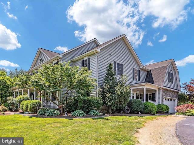 view of front of house featuring an attached garage, aphalt driveway, a front lawn, and roof with shingles