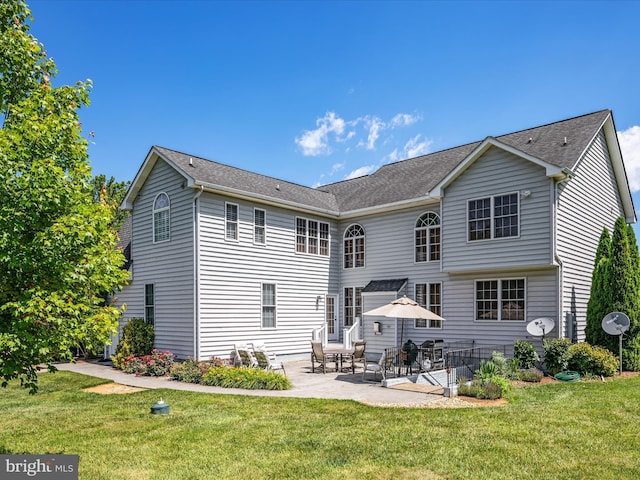 back of house with a patio area, a shingled roof, and a lawn