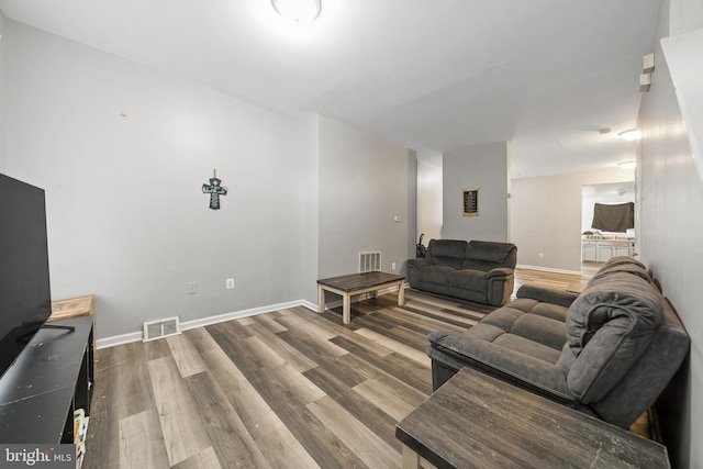 living room with baseboards, visible vents, and wood finished floors