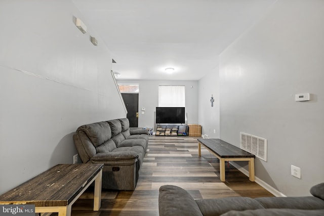 living room with baseboards, visible vents, and wood finished floors