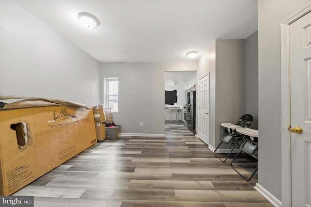 bedroom featuring ensuite bathroom, wood finished floors, freestanding refrigerator, and baseboards