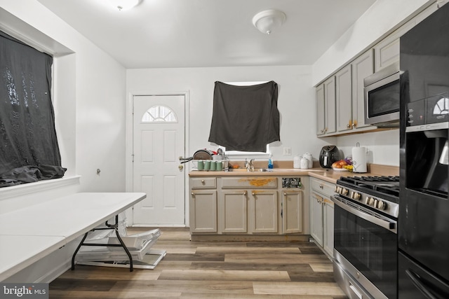 kitchen featuring appliances with stainless steel finishes, light countertops, a sink, and light wood finished floors