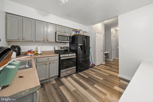 kitchen with appliances with stainless steel finishes, dark wood-style flooring, and gray cabinetry