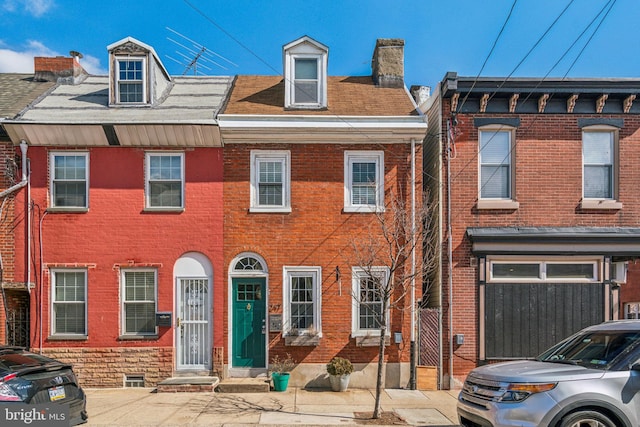 view of property featuring a chimney and brick siding