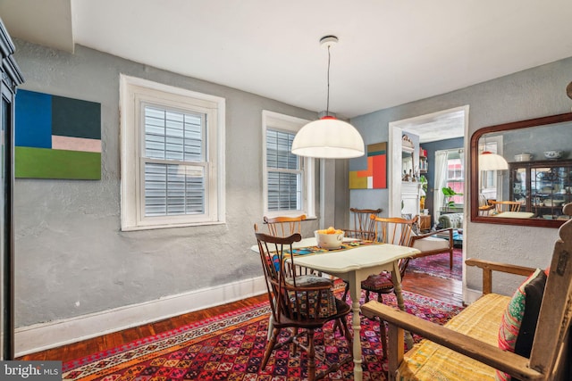 dining space featuring a textured wall, baseboards, and wood finished floors