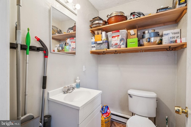 half bath with toilet, vanity, and baseboard heating