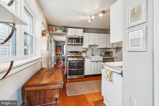 kitchen featuring a toaster, stainless steel appliances, a sink, white cabinets, and light countertops