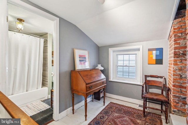 living area featuring lofted ceiling and baseboards